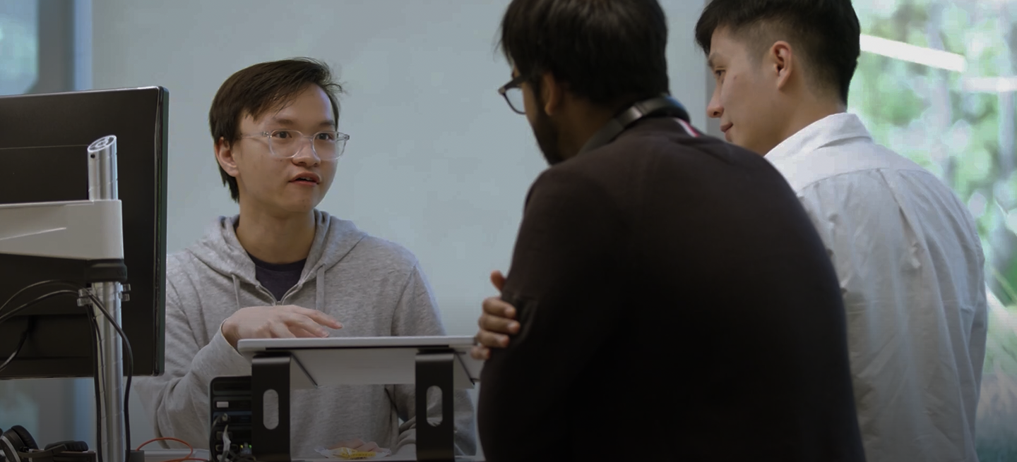 Image de fond de Trois collègues collaborant dans un bureau, discutant du travail autour d'un bureau avec un ordinateur et des documents.